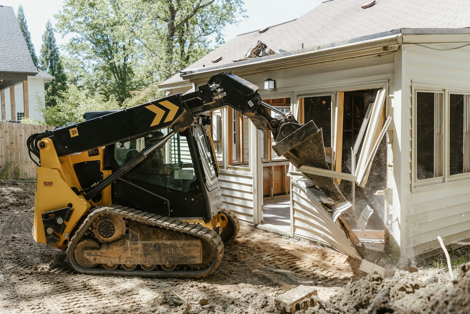 Skid steer clearing a residential addition and churned yard